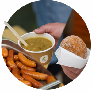 Pyöreä kuva, jossa näkyy kolme ruokaa: hernekeitto puulusikalla, tarjotin täynnä grillimakkaroita ja sokerinen munkki lautasliinassa.