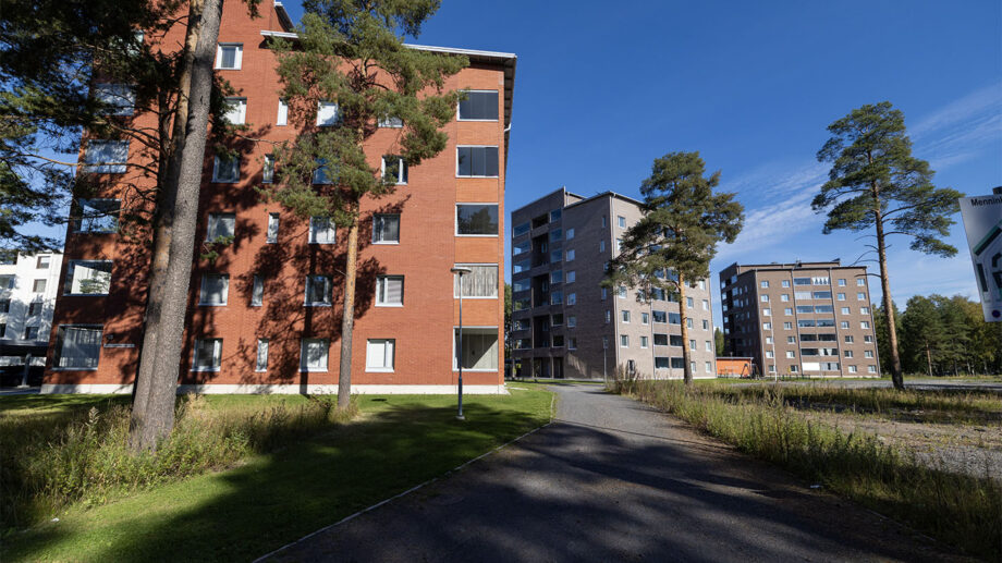 Kaksi asuinkerrostaloa varjoisalla pihapolulla, taustalla useampia rakennuksia.