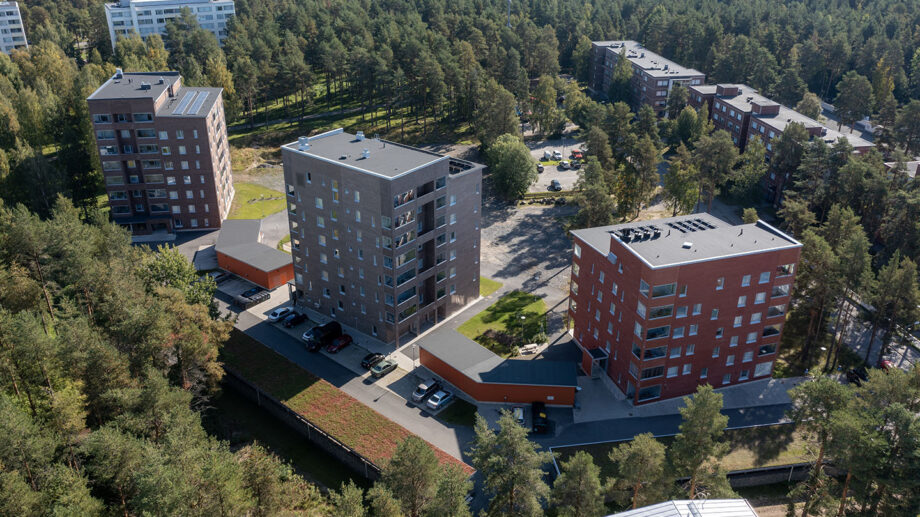 Ilmakuva kahdesta punatiilisestä asuinkerrostalosta metsäisellä alueella.