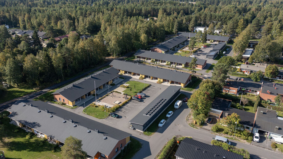 Ilmakuva useasta rivitalosta metsäisessä ympäristössä, pysäköintialue keskellä.