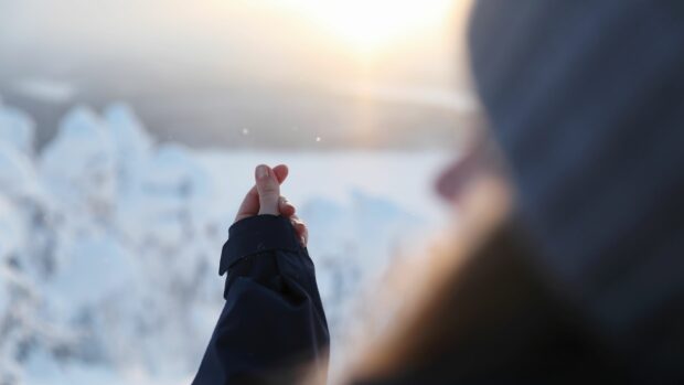 talvinen kuva, jossa näkyy naisen sormet kohdistettuna. Taustalla talvinen tunturimaisema.