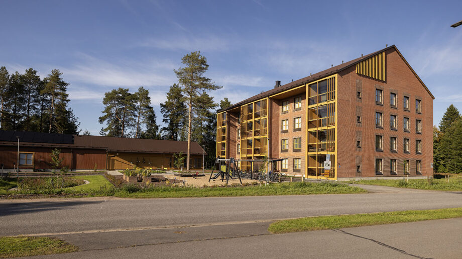 Kolmikerroksinen puu- ja tiiliverhottu asuinrakennus kadun varrella, aurinkoinen sää.