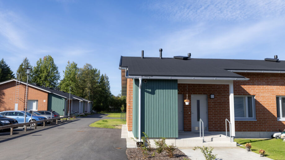 Vaaleasävyinen rivitalo, sisäänkäynti ja asfaltoitu kulkutie.