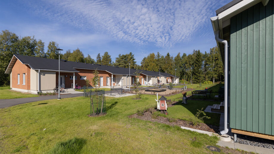 Yksikerroksinen rivitalo, punatiilinen julkisivu ja nurmipiha etualalla.