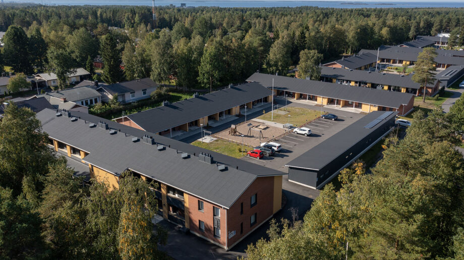 Ilmakuva rivitaloalueesta metsän laidalla, sisäpiha ja parkkialue näkyvissä.