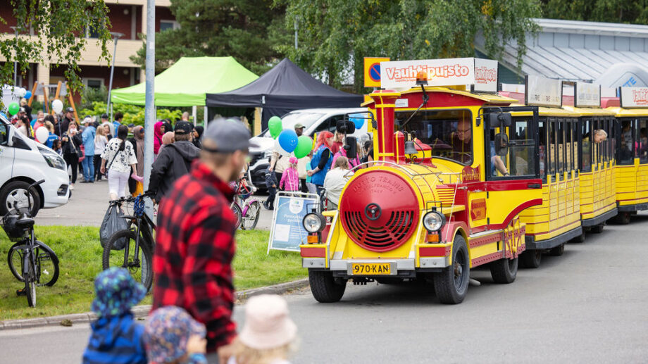 Potnapekka tapahtumassa pysäköitynä. Taustalla näkyy tapahtuman telttoja ja ihmisiä. Etualalla mies kävelee lasten kanssa.