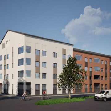 Uusi kerrostalo, jossa valkoinen ja punatiilinen julkisivu, moderni asuinrakennus rauhallisella alueella.