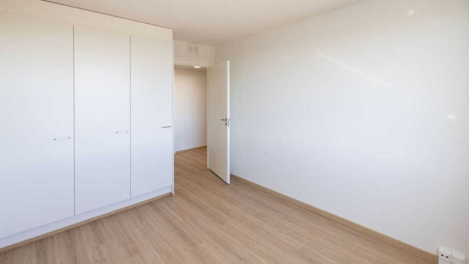 Makuuhuone, kaapistot ja avoin ovi, josta näkymä käytävälle