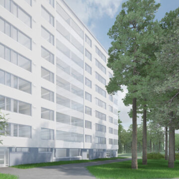 Vaalea, moderni kerrostalo metsäisessä ympäristössä. Rakennuksessa on useita kerroksia ja lasitettuja parvekkeita, ja sen edessä kulkee polku nurmialueen halki. Oikealla puolella kasvaa korkeita mäntyjä.