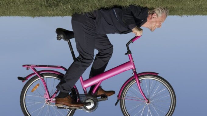 Mies ajaa pinkillä polkupyörällä, kuva käännetty ylösalaisin.