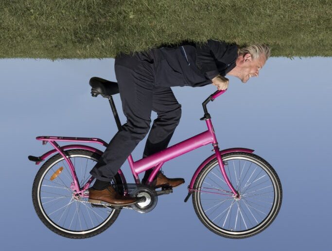 Mies ajaa pinkillä polkupyörällä, kuva käännetty ylösalaisin.